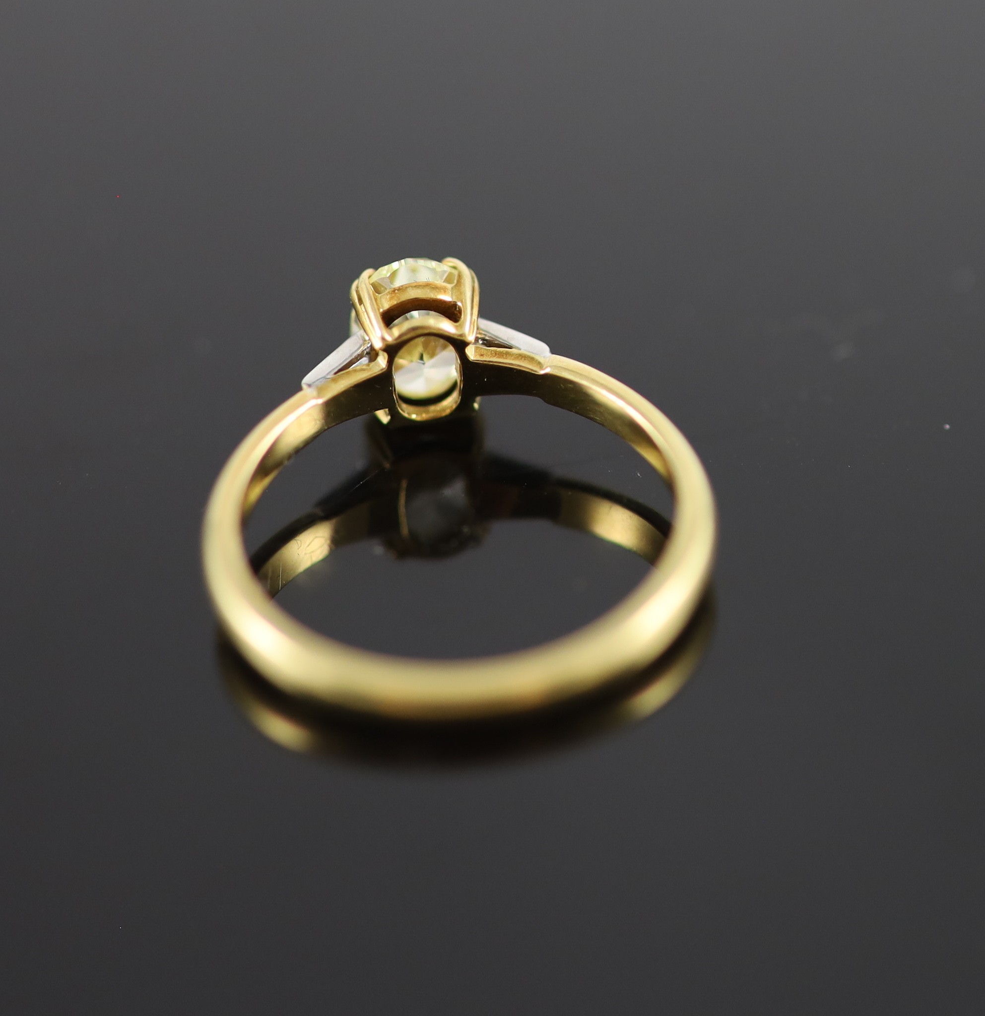 A modern 18ct gold and single stone oval fancy yellow diamond ring, with trapeze cut diamond set shoulders